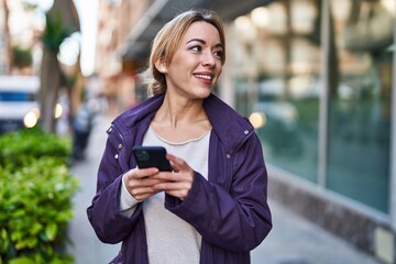 Fototapeta premium Young woman smiling confident using smartphone at street