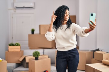 Fototapeta na wymiar Middle age hispanic woman moving to a new home taking selfie picture smiling with an idea or question pointing finger with happy face, number one
