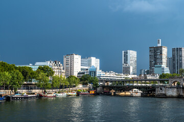 River Seine In Paris, France With Promenade, Anchored Houseboats And Modern Office Buildings