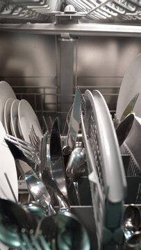 Forward dolly shot of dishwasher machine with dishes and silverware