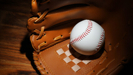 Baseball ball in a glove on the wooden table.