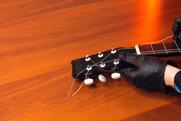 man with guitar, master hand tuner in gloves with classical guitar strings and pegs tuning, wooden...