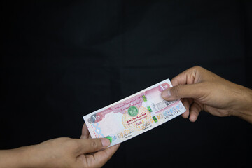 man giving money, United Arab Emirates dirham currency, to his partner.