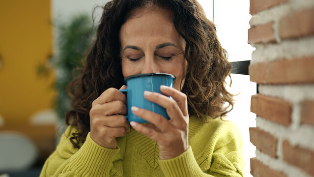 Middle Age Hispanic Woman Drinking Coffee Standing At Home