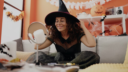 Middle age hispanic woman wearing witch costume for halloween party at home