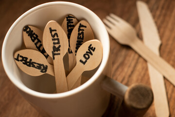Bunch of wooden spoons are inside a white coloured coffee mug each spoon hand written with words like love,trust,patience,empathy,honesty the essence of relationship in a wooden background