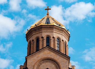 Part of Tsminda Sameba - Holy Trinity Church in Tbilisi, Georgia on a sunny day against a blue sky.