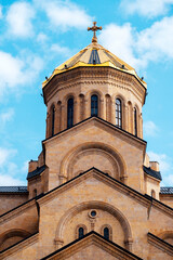 Fototapeta na wymiar Part of Tsminda Sameba - Holy Trinity Church in Tbilisi, Georgia on a sunny day against a blue sky.