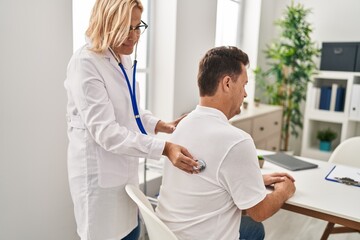 Obraz premium Middle age man and woman doctor and patient examining vision having medical consultation at clinic