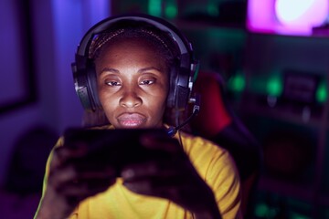 African american woman streamer playing video game using smartphone at gaming room