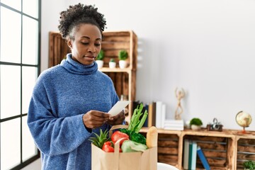 African american woman reading food receipt at home