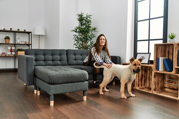 Young hispanic woman smiling confident sitting on sofa with dog at home