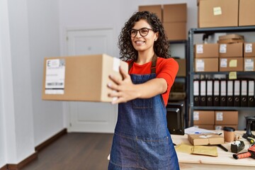 Young latin woman ecommerce business worker holding package at office