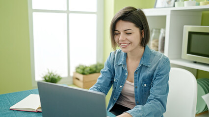 Young caucasian woman using laptop sitting on the table at home