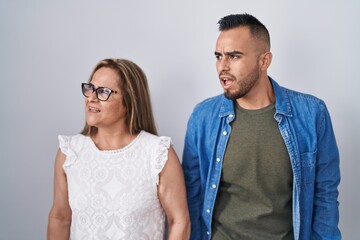 Hispanic mother and son standing together angry and mad screaming frustrated and furious, shouting with anger. rage and aggressive concept.