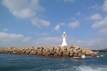 White lighthouse and sky above breakwater