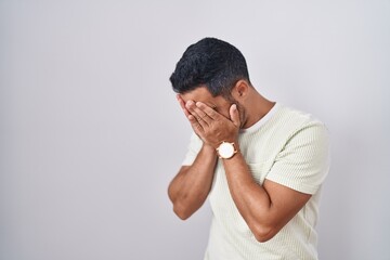 Hispanic man with beard standing over isolated background with sad expression covering face with hands while crying. depression concept. - obrazy, fototapety, plakaty