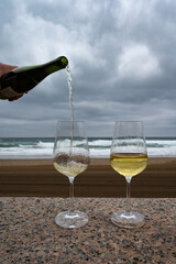 Pouring of txakoli or chacolí slightly sparkling very dry white wine produced in Spanish Basque Country served outdoor with view on Bay of Biscay, Atlantic Ocean