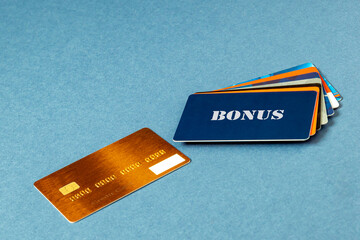 Gold color credit card, BONUS card, fan sales cards lie on a blue background. Pile of credit cards for different purposes