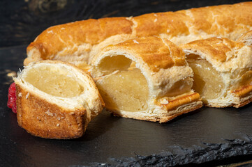 Fresh baked Dutch filled spicy cookies from puff pastry with almonds in autumn colors on dark stone