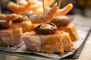 Typical snack of Basque Country, pinchos or pinxtos skewers with small pieces of bread, sea food,...