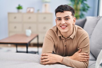 Young non binary man smiling confident lying on sofa at home