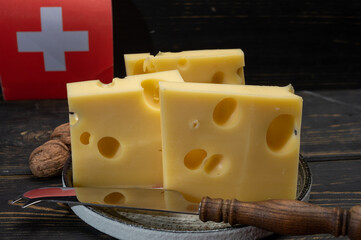 Block of Swiss medium-hard yellow cheese emmental or emmentaler with round holes and cheese knife...