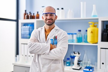 Young man scientist standing with arms crossed gesture at laboratory - obrazy, fototapety, plakaty