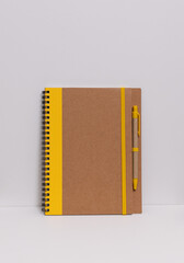 yellow and brown notebook and pencil, white background