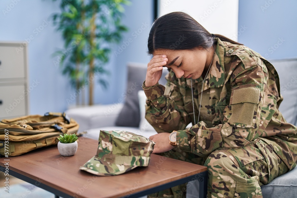 Wall mural young hispanic woman army soldier depressed sitting on sofa at home - Wall murals
