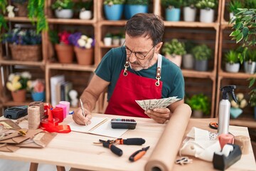 Fototapeta premium Middle age man florist counting dollars at florist