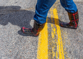 Fashionable rubber boots walking across a highway