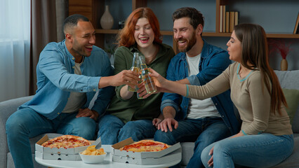 Group of happy multiethnic diverse friends having fun clinking bottled beer at home drinking alcohol at festive table with pizza adults people celebrate together Friday party birthday new year holiday