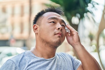 Young chinese man using napkin sweating at street