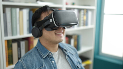 Young chinese man student smiling confident using virtual reality glasses at library university