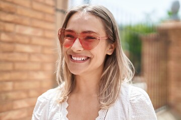 Young caucasian woman smiling confident wearing heart sunglasses at street