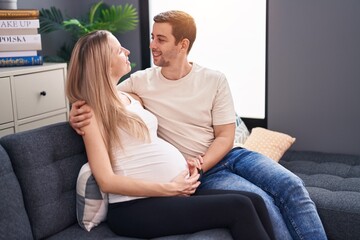 Man and woman couple expecting baby hugging each other at home