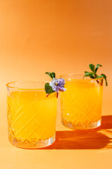 orange cocktail with mint and violet on orange background