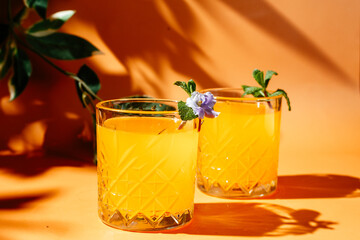 orange cocktail with mint and violet on orange background