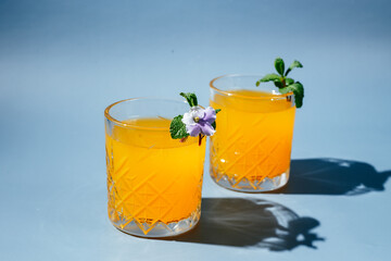 orange cocktail with mint and orange chips on a blue background