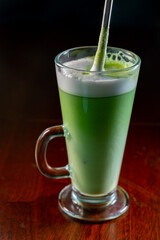 Glass of green Matcha tea made from finely ground powder of specially grown and processed green tea leaves consumed in East Asia with whipped milk