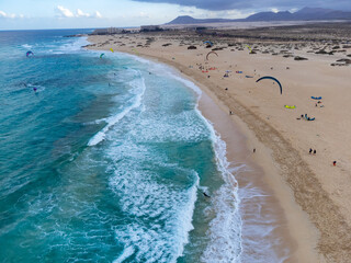 Fototapeta na wymiar Aerial view on white sandy Corallejo dunes, beach, ocean water and kite surfers at winter