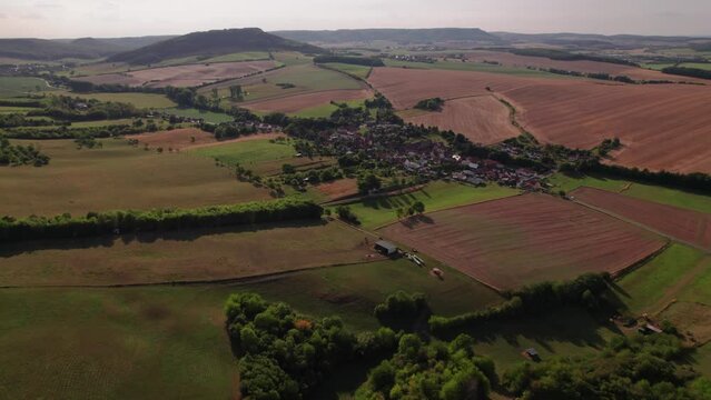 Aer ial view of a German village surrounded by meadows, farmland and forest in Germany.
