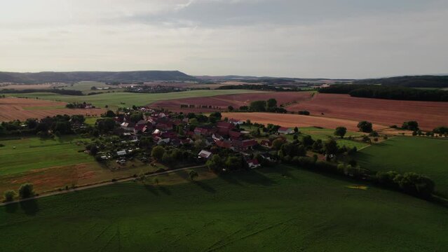Aer ial view of a German village surrounded by meadows, farmland and forest in Germany.
