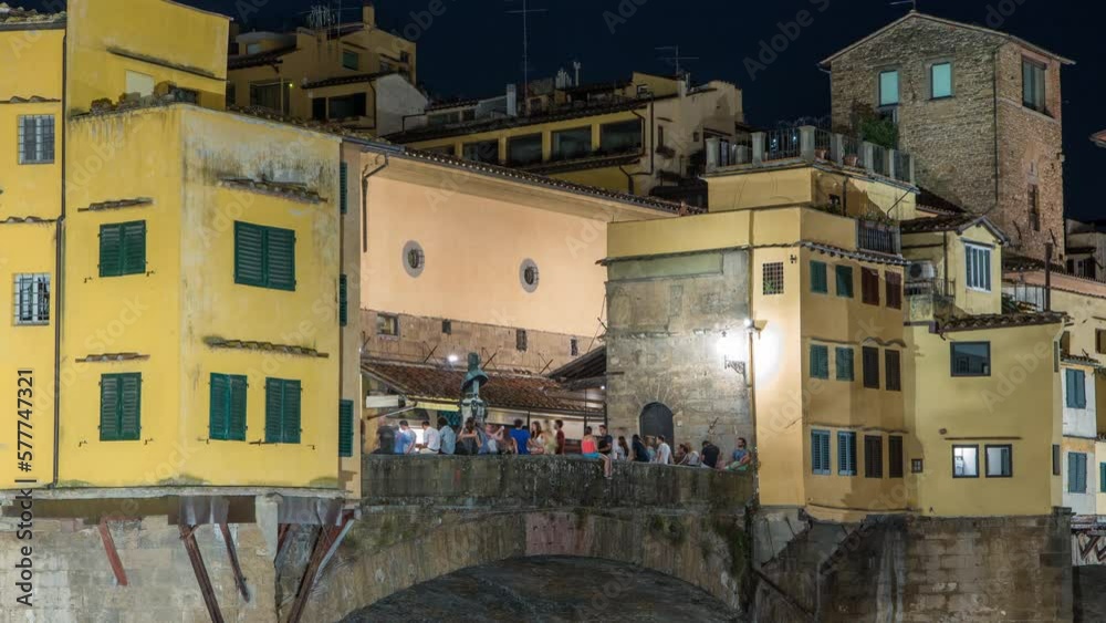 Poster famous ponte vecchio bridge over the arno river timelapse in florence, italy, lit up at night. crowd