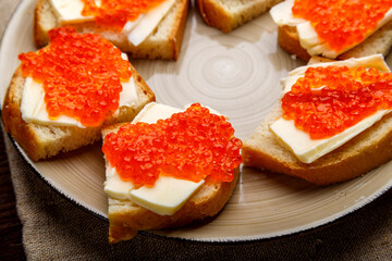 Canape with red trout and butter in a plate on a gray table.close-up.