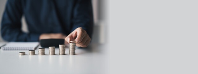 Man hand putting coins on stack of money, saving money concept.