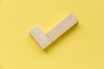 Checklist concept. Accomplishment of objectives or goals. Wooden check mark on yellow background.