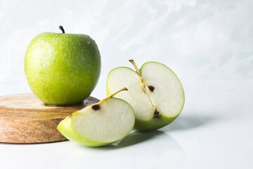 Green apples and apple slices on wooed light background.