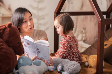 mom reads a book to a girl with down syndrome before going to bed, children's fairy tales and stories